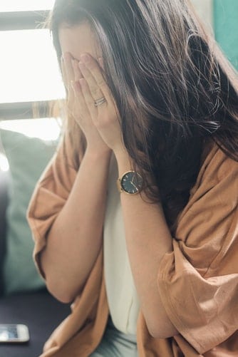 Woman covering face with her hands.