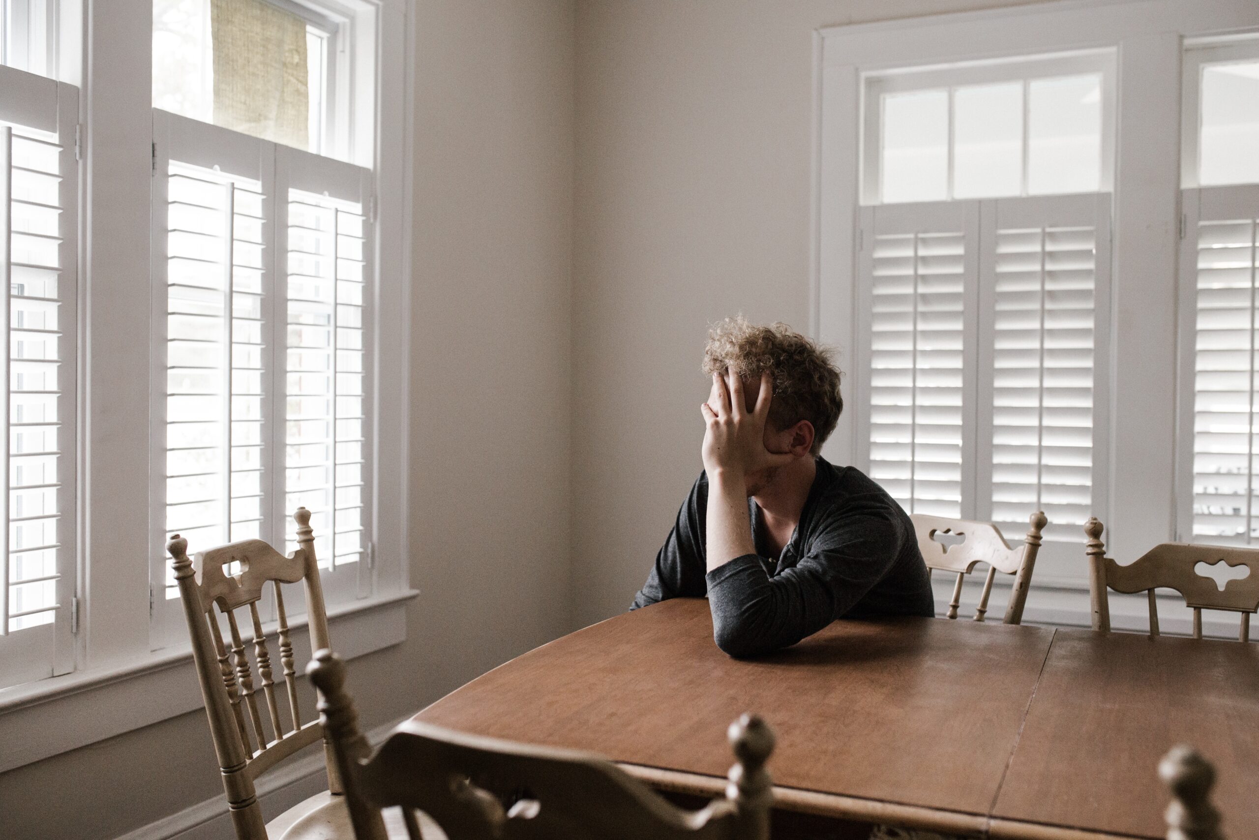 Depressed man sitting with head in hands at his table.
