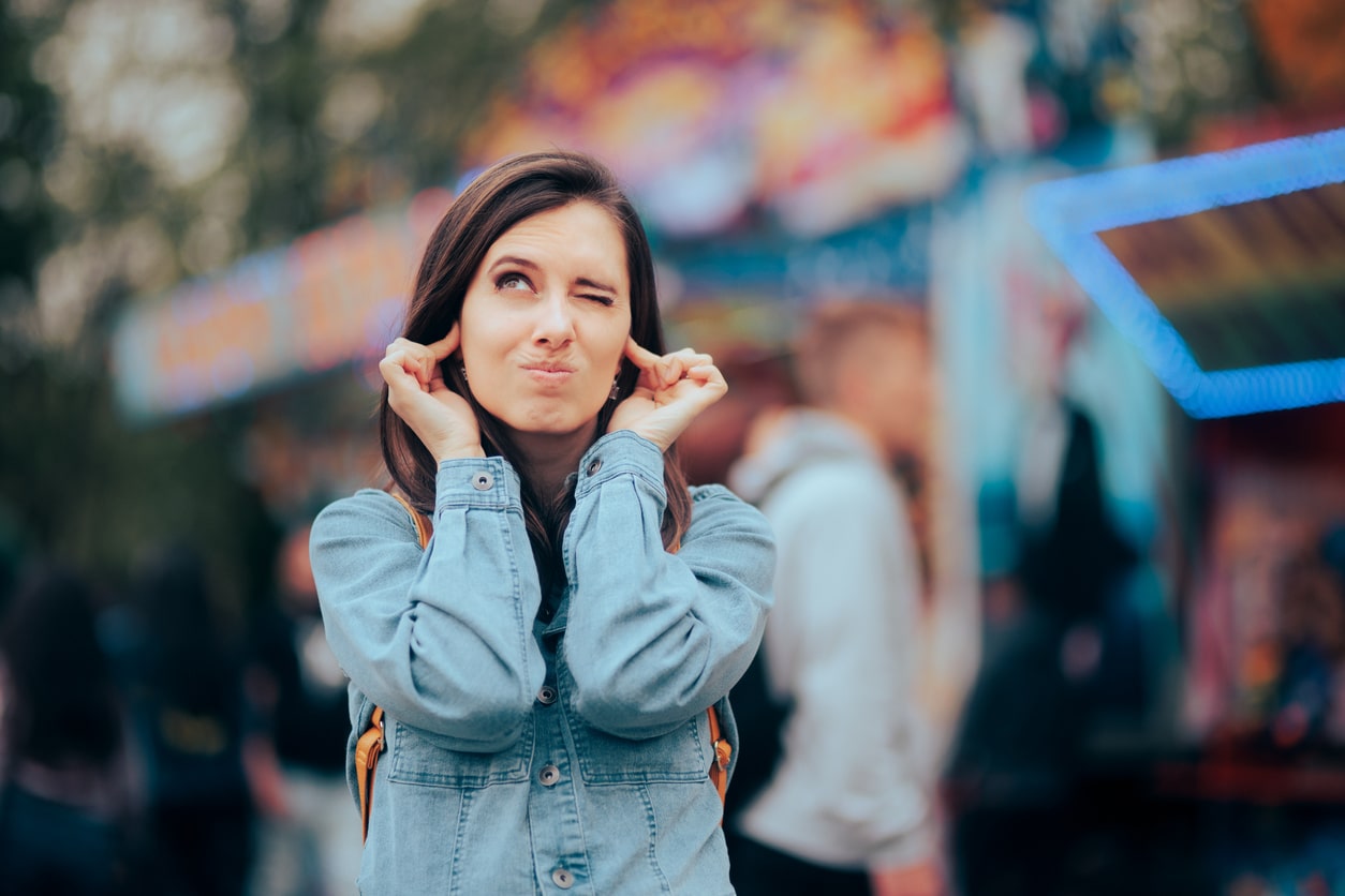 Woman covering her ears around loud noise