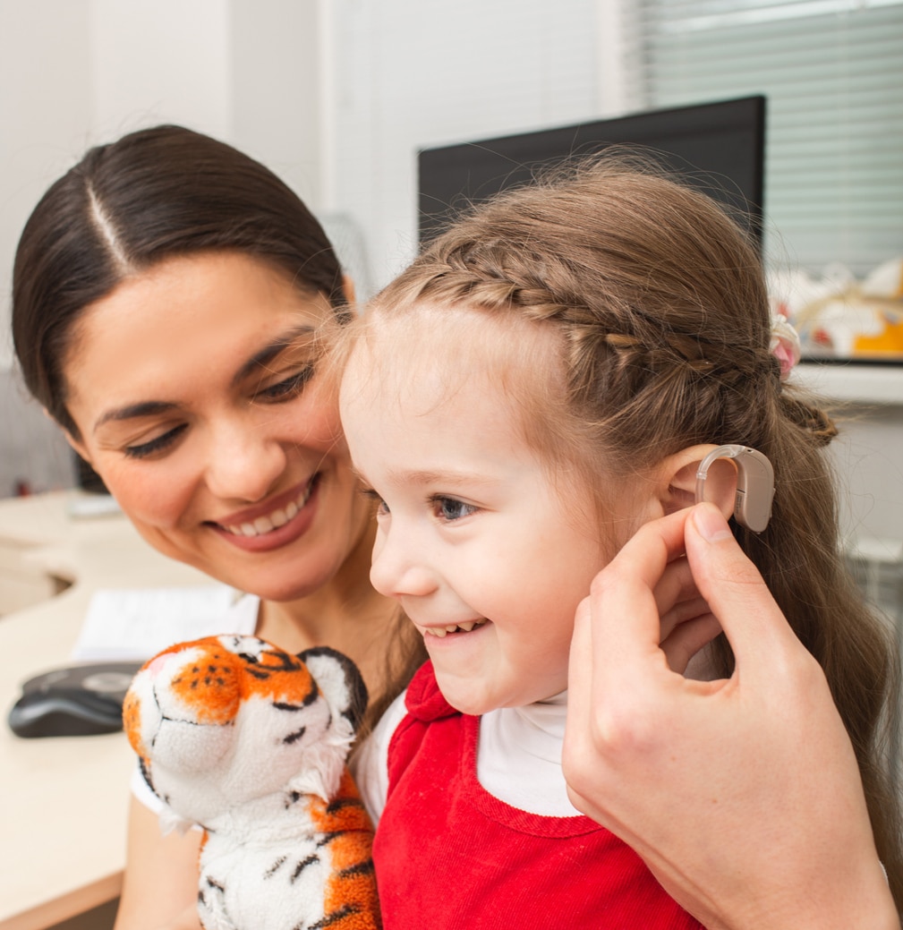 Young girl looking happy getting her first hearing aid